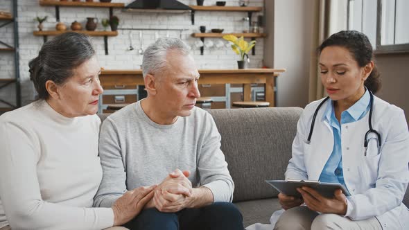 Woman Doctor Saying Diagnosis to Confused Senior Male Sitting on Couch During Medical Consultation