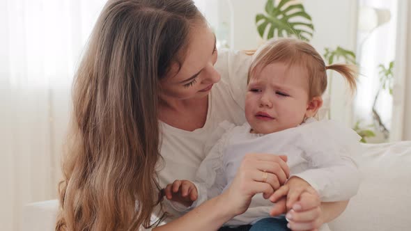 Young Caucasian Mother with Crying Child Sad Sick Little Girl Baby Embracing at Home Caring Mom