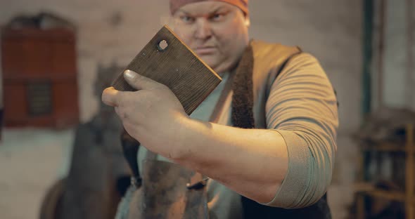 Blacksmith Looks at a Wooden Board with a Hole
