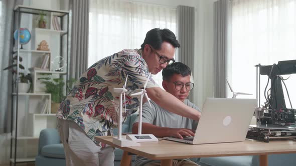 Father Teach His Son Using Laptop Computer Programming Electric Wind Turbine Model And 3D Printer