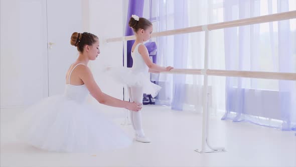 Ballet Teacher in White Tutu Is Training Little Girl Near the Barre Stand.