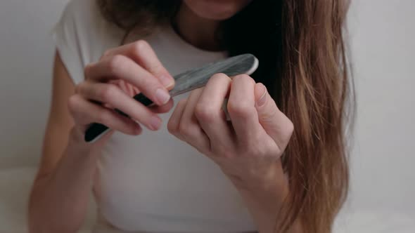 Woman Using Emery Board on Fingernails