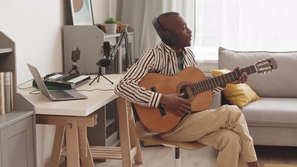 African Guitarist Wearing Headphones Playing Acoustic Guitar