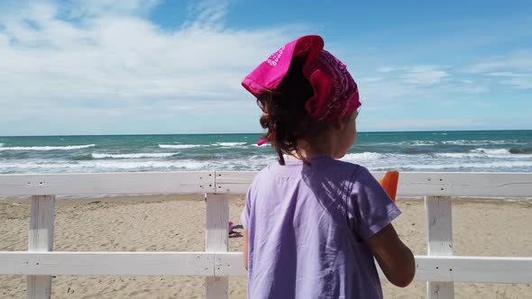 Baby Girl Child Eat Popsicle at the Beach Bar on Wind Sea with Pink Bandana