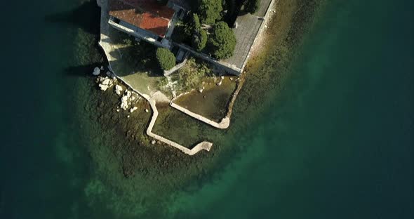 Man made island in Montenegro, aerial footage, birds eye view of island with clear water.