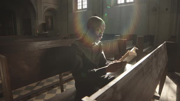 Priest Sitting on Bench and Reading in Lutheran Church