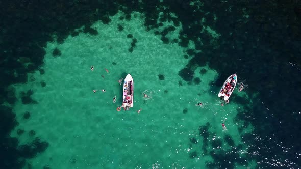 Aerial View of Tourists Relaxing and Swimming in the Turquoise Sea Water Next To Tourist Boats
