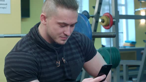 Man Using Smartphone in the Gym After Training