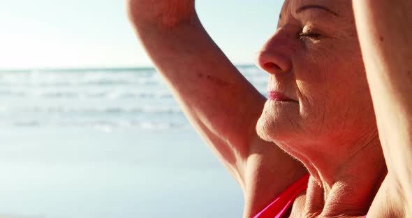 Senior woman doing yoga at beach