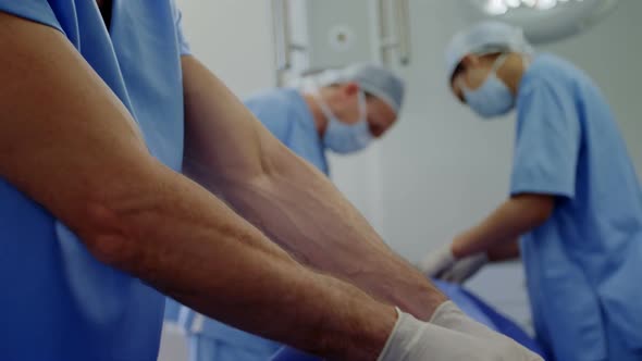 Multi-ethnic group of male and female surgeons working together in a hospital operating theatre, wea