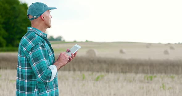 Farmer Using Digital Tablet While Examining Farm