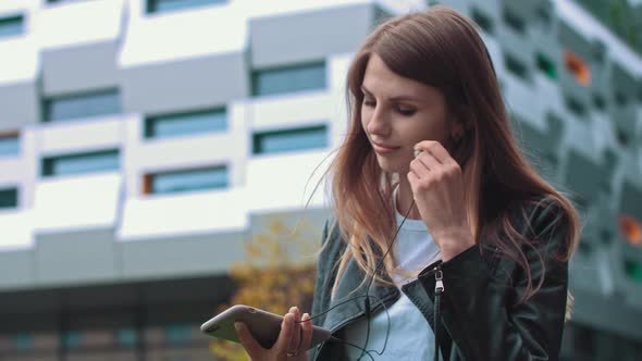 Attractive Girl Student in Modern Clothes Uses a Mobile Phone to Listen to Good