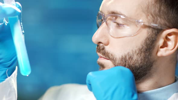 Professional Male Researcher Shaking Glass Beaker with Blue Reactive Side View