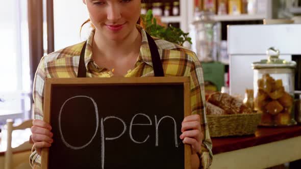 Portrait of waitress showing chalkboard with open sign