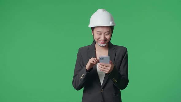 Smiling Asian Female Engineer Using Smartphone And Walking In The Green Screen Studio