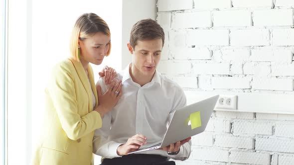 Young Office Workers Discussing Online Project Using Laptop at Modern Office