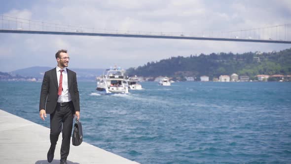 Happy and smiling businessman. He is walking on the Bosphorus in the city.