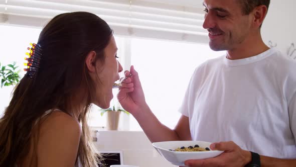Young man feeding his woman in the kitchen at home 4k