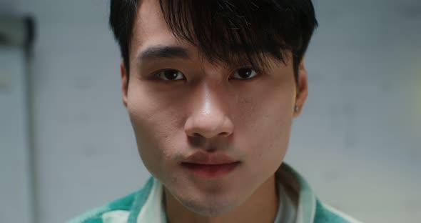 Closeup Face of a Young Asian Man Raising His Eyes to the Camera with a Smile