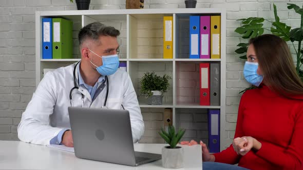 Doctor and patient wears protective masks on faces in hospital communicates talk