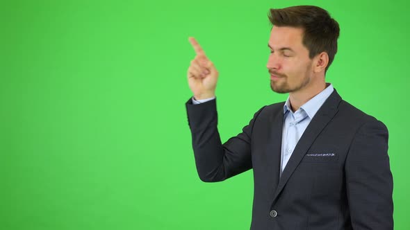 A Young Handsome Businessman Points at Bullet-point Text, Smiles and Nods - Green Screen Studio