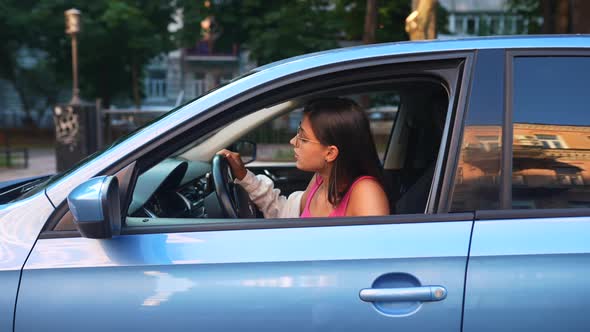 A Young Angry Woman Peeks Out of the Car Window