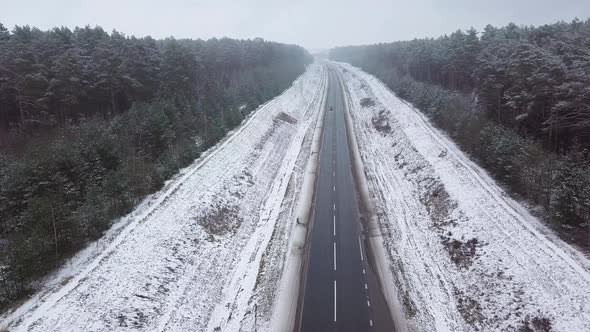 Winter highway, car and truck traffic. On the sides of the forest.