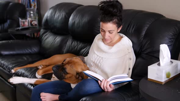 Woman reading a novel while dog relaxing on her lap