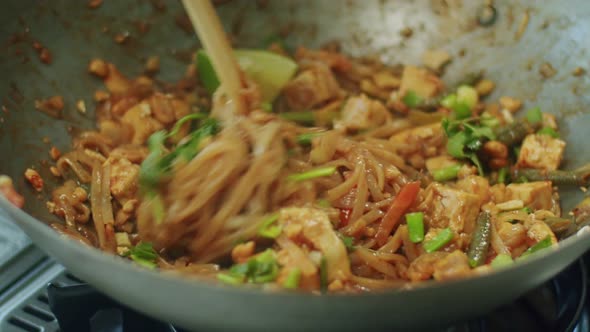 Woman mixing delicious wok noodles with chopsticks