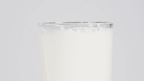 Close up pouring fresh milk in glass over white
