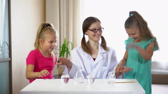 Small children with a teacher in the school laboratory conducting chemical experiments.