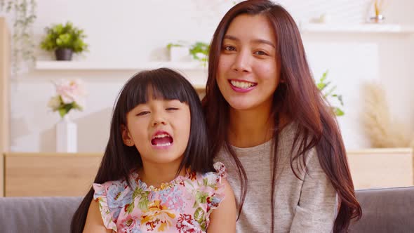 Happy mother and daughter looking at camera sending smile and cheerful face together. Funny happy mo