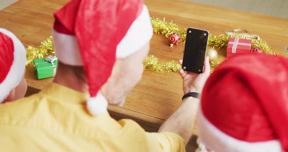 Rear view of father and two sons having a videocall on smartphone with copy space during christmas