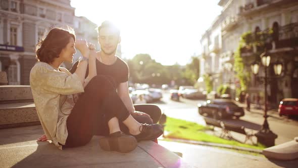 Young Beautiful Couple Taking Pictures Smiling Speaking Sitting in City Park