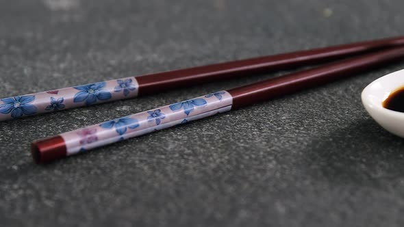 Chopsticks and soy sauce on black stone slate