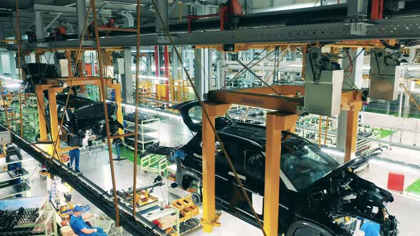 Car Mechanics Assembling Vehicles on a Production Line