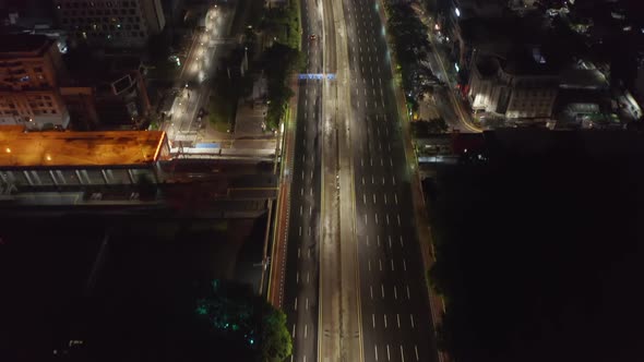 Aerial Tilting Shot Following One Police Car on Empty Multi Lane Motorway at Night in Large