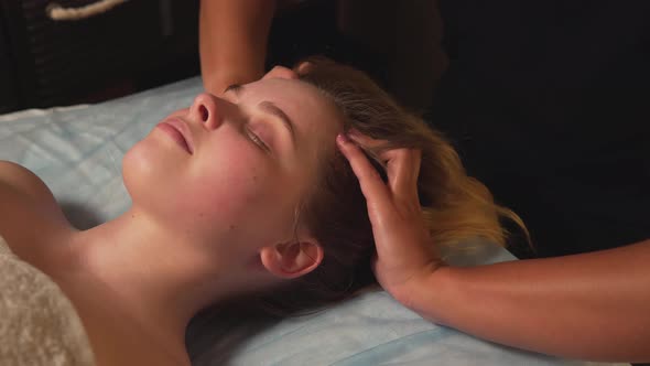 A Young Beautiful Woman Enjoys a Head Massage at the Massage Spa