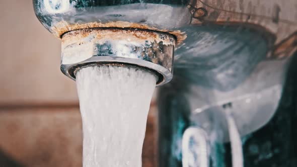 Water Flows From an Old Contaminated Tap with Calcium and Grime Into a Sink