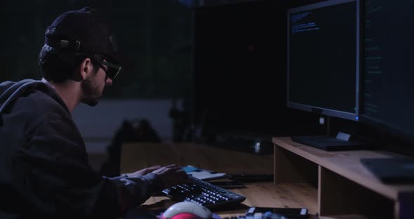 Computer hacker sitting in a dark room hacking security systems