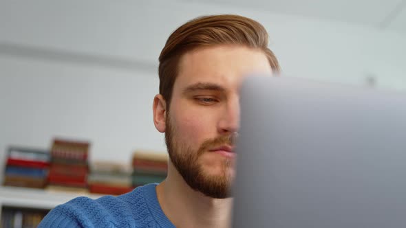 Thoughtful man thinking about online project while looking at laptop