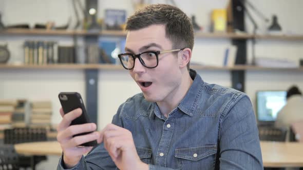 Excited Young Man Enjoying Success While Using Smartphone