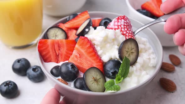 Cottage cheese with strawberries, nuts and blueberries in gray bowl for breakfast.