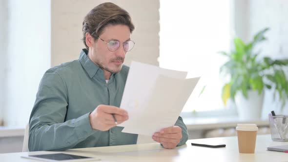 Middle Aged Man Reading Documents in Office