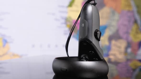 Virtual reality helmet controller on a black mirrored background against a world map