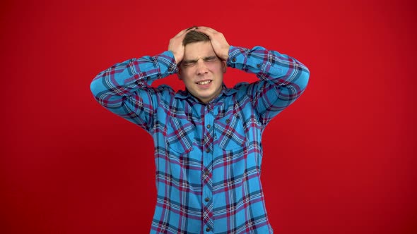 A Young Man Has a Headache and Holds It in His Hands