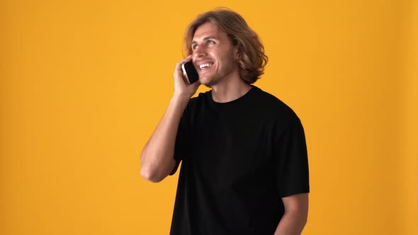 Laughing blond man talking by phone