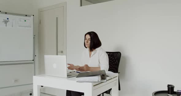 Female Teacher Conducts an Online Lecture on a Laptop in the Office