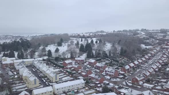 Forward tracking drone shot of snowy Exeter over a wooded area