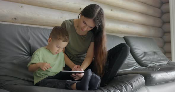 Mum Works with Her Son on a Child Development App on a Digital Tablet